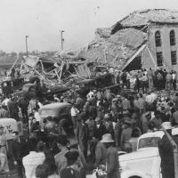 Crowds of people and emergency vehicles surrounding damaged school.